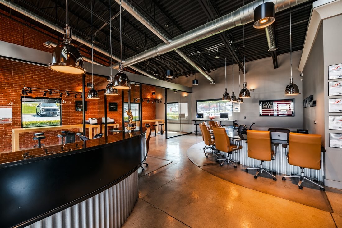 Dealership sales floor with brick, steel and orange chairs