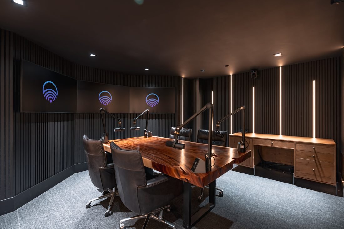 Podcast studio with a live edge table and boom microphones